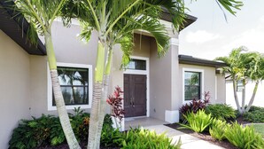 A modern house with a well-maintained garden, a front door, and a visible window.