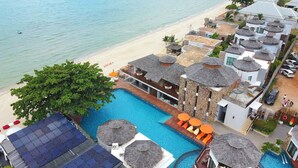 A resort with a swimming pool, beach, and multiple buildings with unique roofs. - Yotaka Khanom (Khanom)