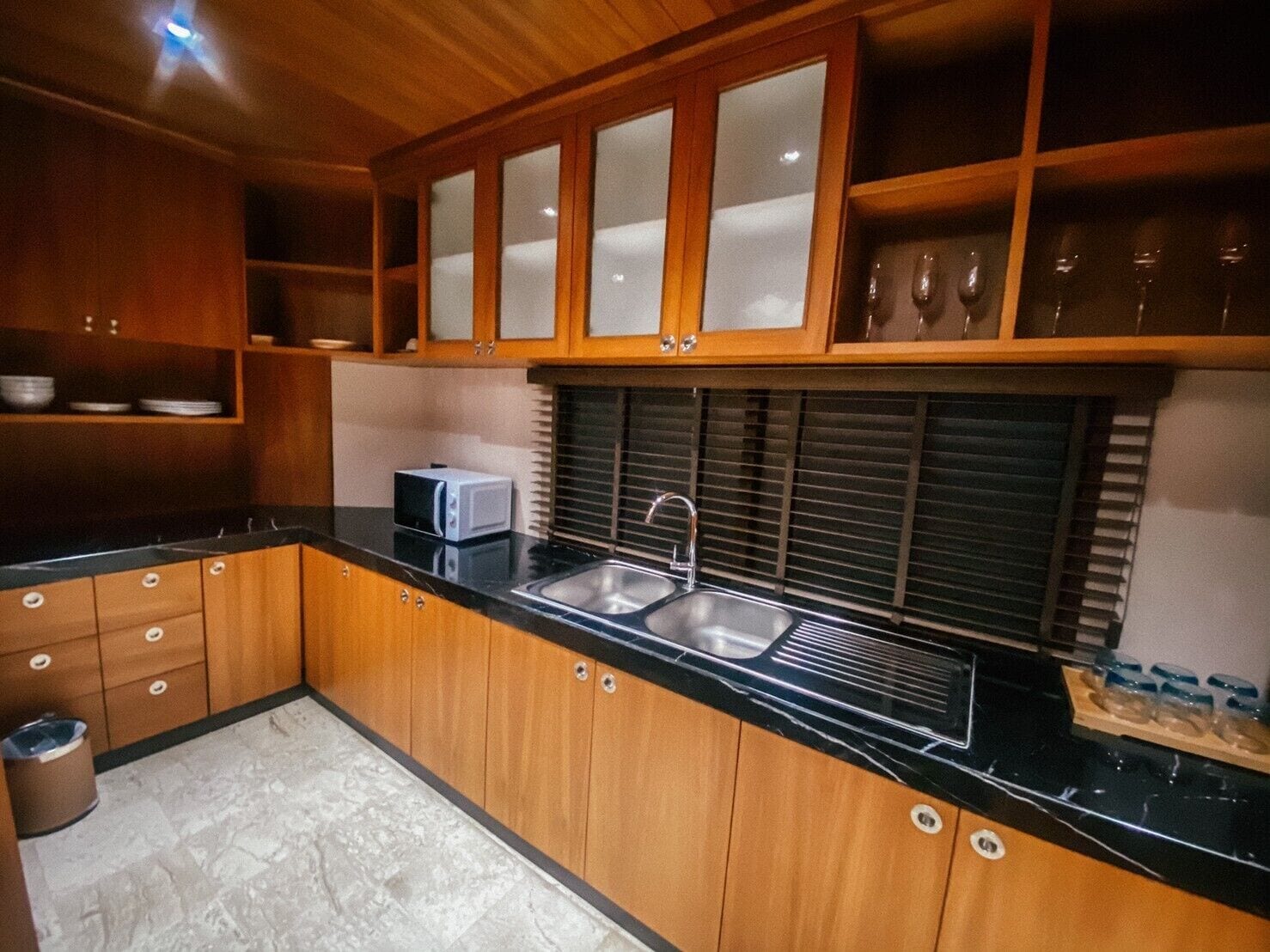 A kitchen with wooden cabinets, a black countertop, a sink, and a microwave.