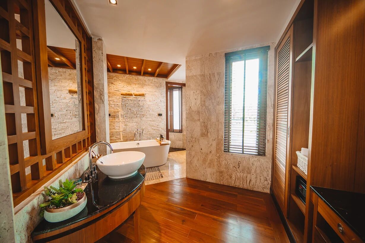 A modern bathroom with a freestanding bathtub, a large mirror, and a wooden floor.