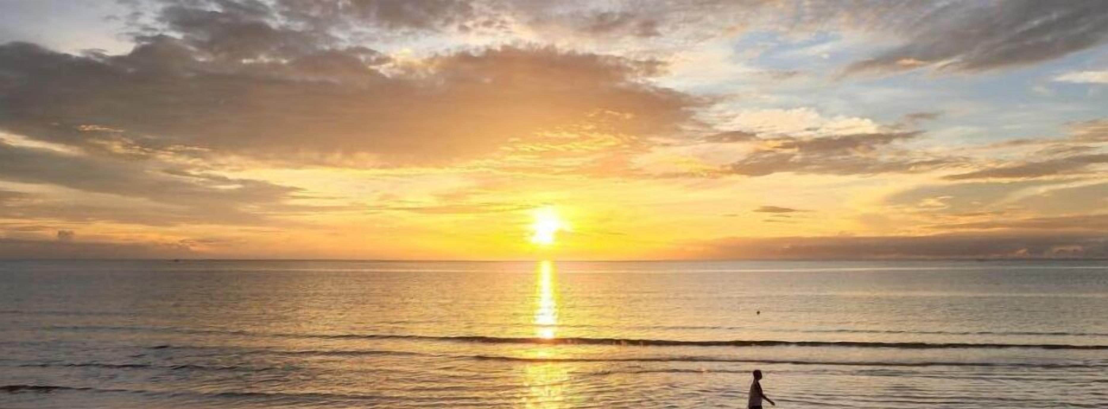 Tramonto sull'oceano con cielo sereno e acque calme.