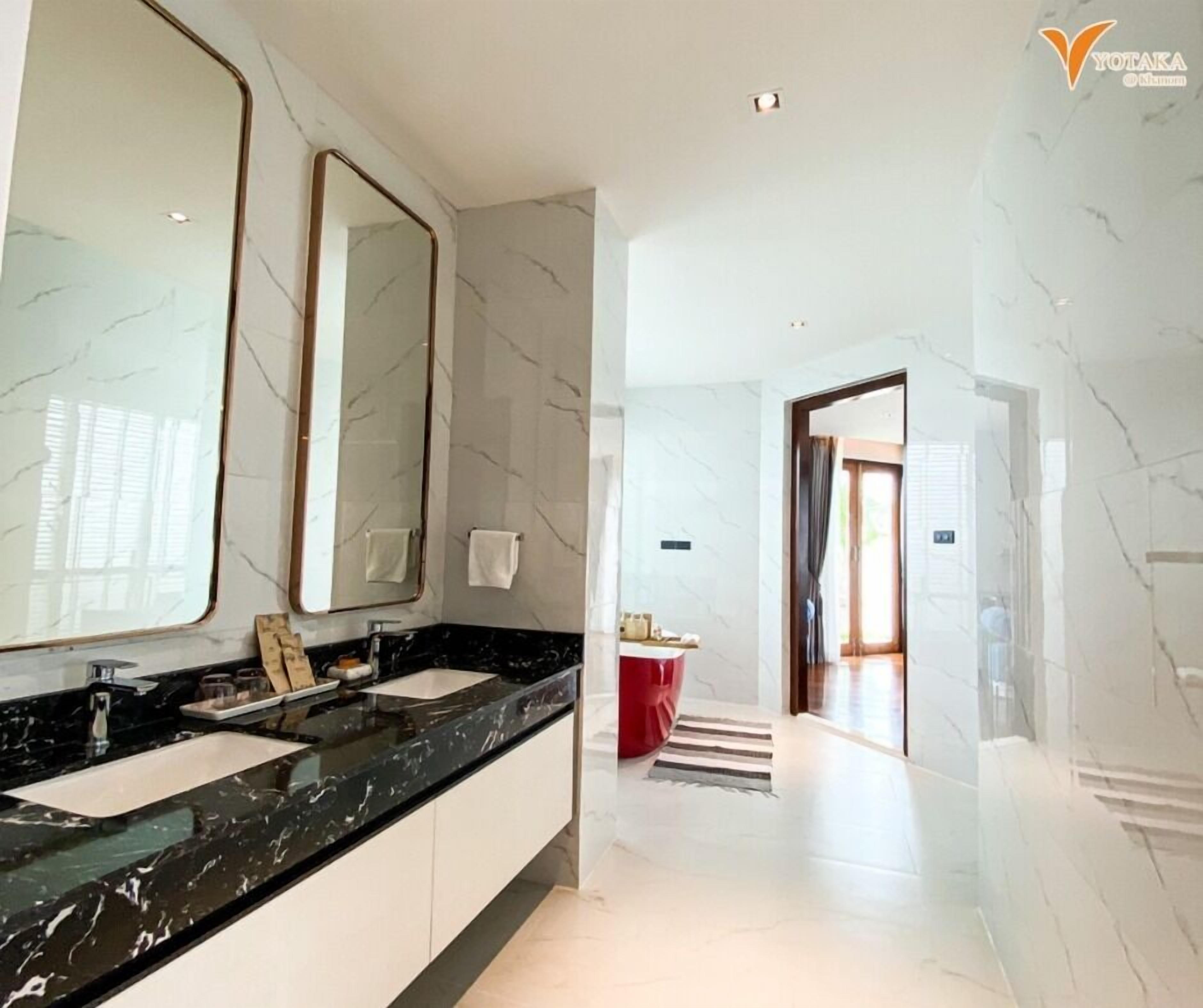 A modern bathroom with a large mirror, black marble countertop, and white marble walls.