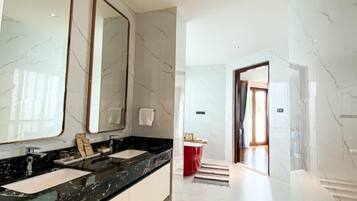 A modern bathroom with a large mirror, black marble countertop, and white marble walls.