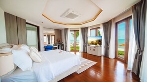 A spacious hotel room with a large bed, a TV, and a view of the beach. - Yotaka Khanom (Khanom)