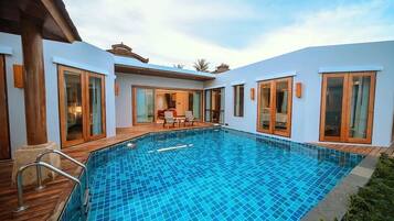 A modern pool area with glass doors and a wooden deck.