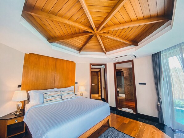Un dormitorio con techo de madera, una cama grande, lámparas de noche y vistas a una piscina a través de una ventana.