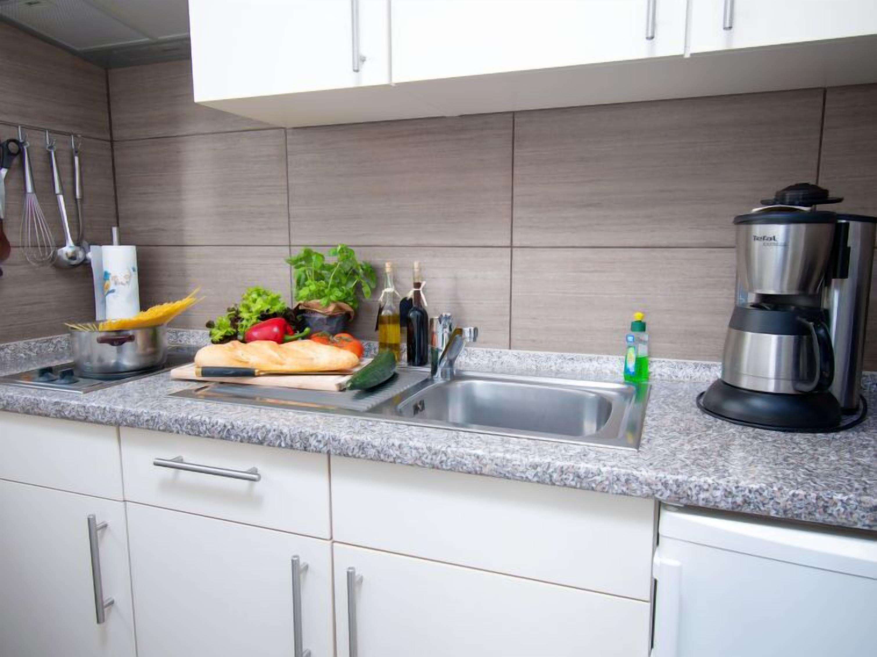 A kitchen with a granite countertop, stainless steel sink, and a coffee maker.