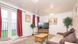 A living room with a sofa, a wooden coffee table, a TV, and a potted plant. - 5 bed house with free secure parking in pleasant quiet location (Wolverhampton)