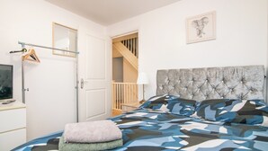 A bedroom with a bed, a mirror, a coat rack, and a staircase leading to another room. - 5 bed house with free secure parking in pleasant quiet location (Wolverhampton)