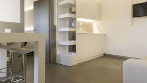 Une cuisine moderne et minimaliste, dotée d’étagères intégrées et d’un téléviseur à écran plat.