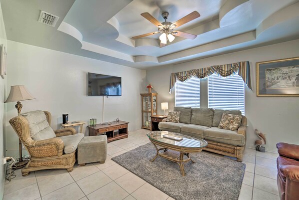 A living room with a ceiling fan, a flat-screen TV, a sofa, a coffee table, and a chair. - Deck & Pool Access: Long Island Village Escape! (Port Isabel)