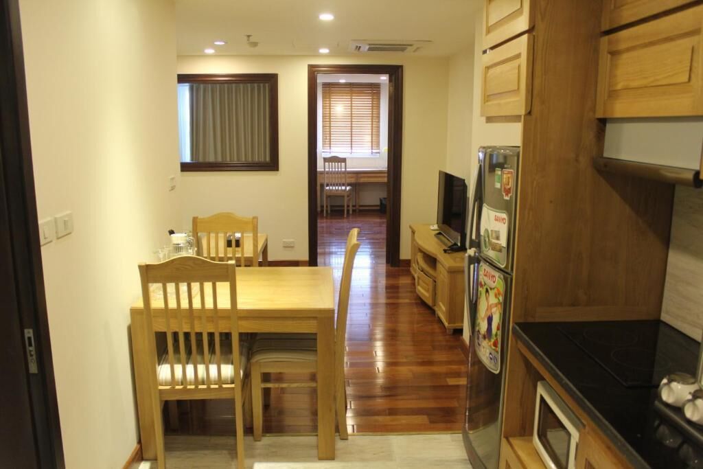 Cocina compacta con armarios de madera, un refrigerador, una estufa y un comedor con mesa y sillas.