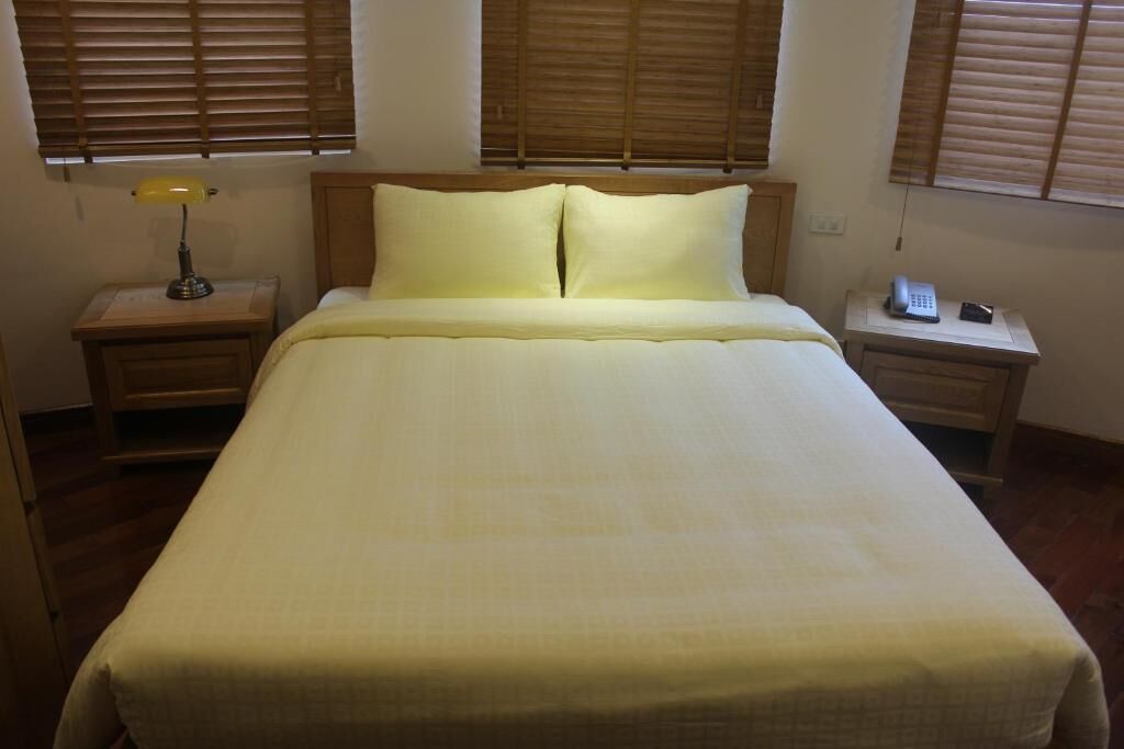 A neatly made bed with a headboard, two bedside tables with lamps, and a telephone on one of the tables.