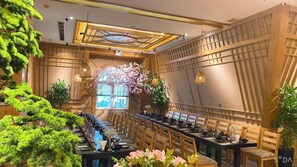 A long dining table with chairs, surrounded by potted plants and a decorative archway with flowers. - Hai Phong Tower (Hai Phong)