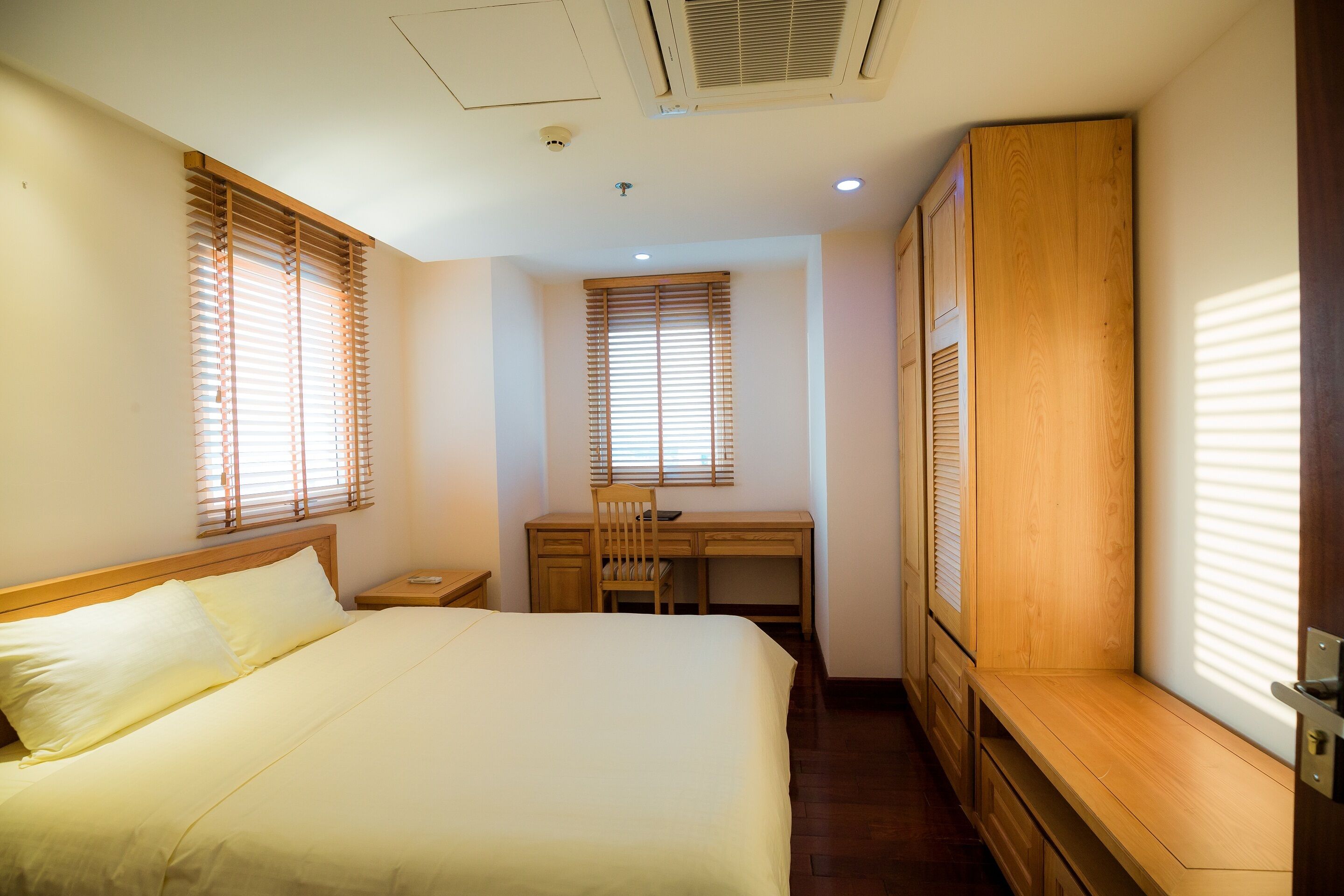 A bedroom with a bed, a desk, and a wardrobe.