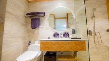 Un baño con inodoro, lavamanos con espejo y ducha.