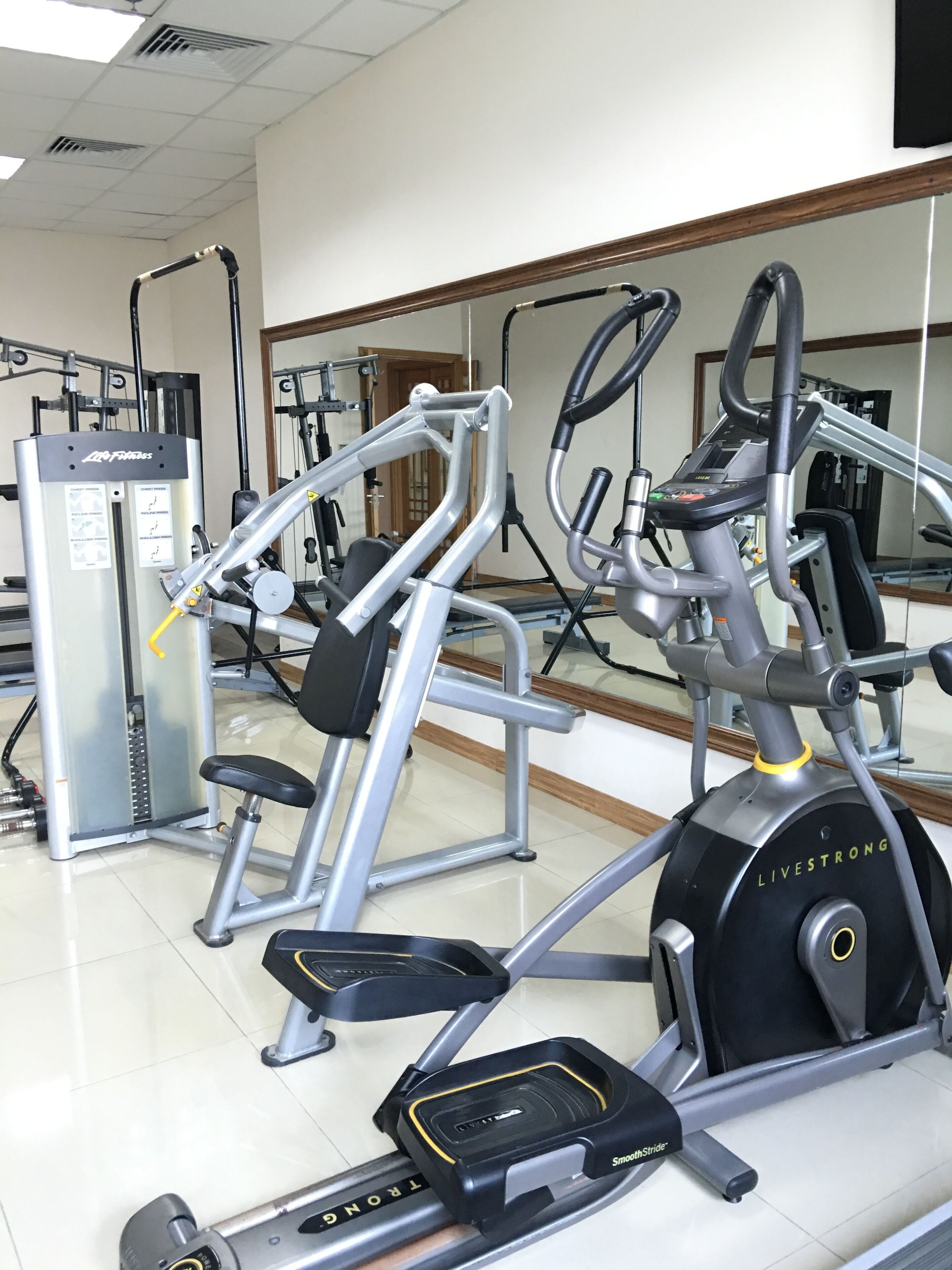 Una palestra con diverse attrezzature per l'allenamento, tra cui un tapis roulant, un ellittica e macchinari per pesi.