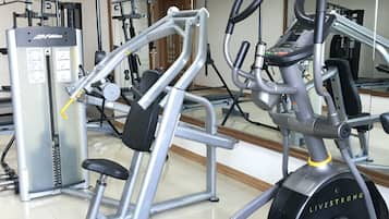 Una palestra con diverse attrezzature per l'allenamento, tra cui un tapis roulant, un ellittica e macchinari per pesi.