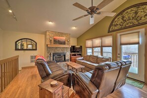 Cozy living area with a stone fireplace, comfortable seating, and large windows.