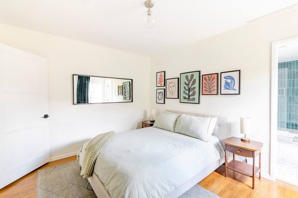 A bedroom with a bed, bedside tables, and a large window.