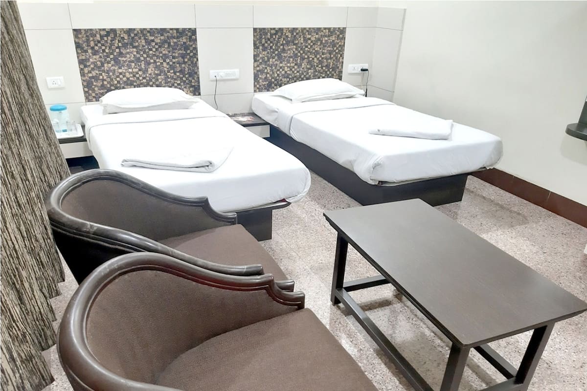 Una habitación de hotel con dos camas individuales, una mesita y un sillón de masaje.