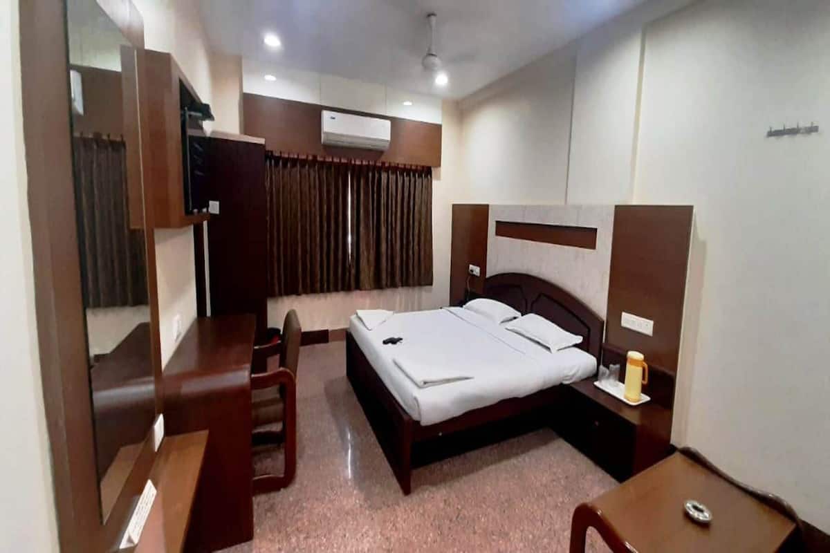 Una habitación de hotel con cama, mesita de noche, silla y escritorio.