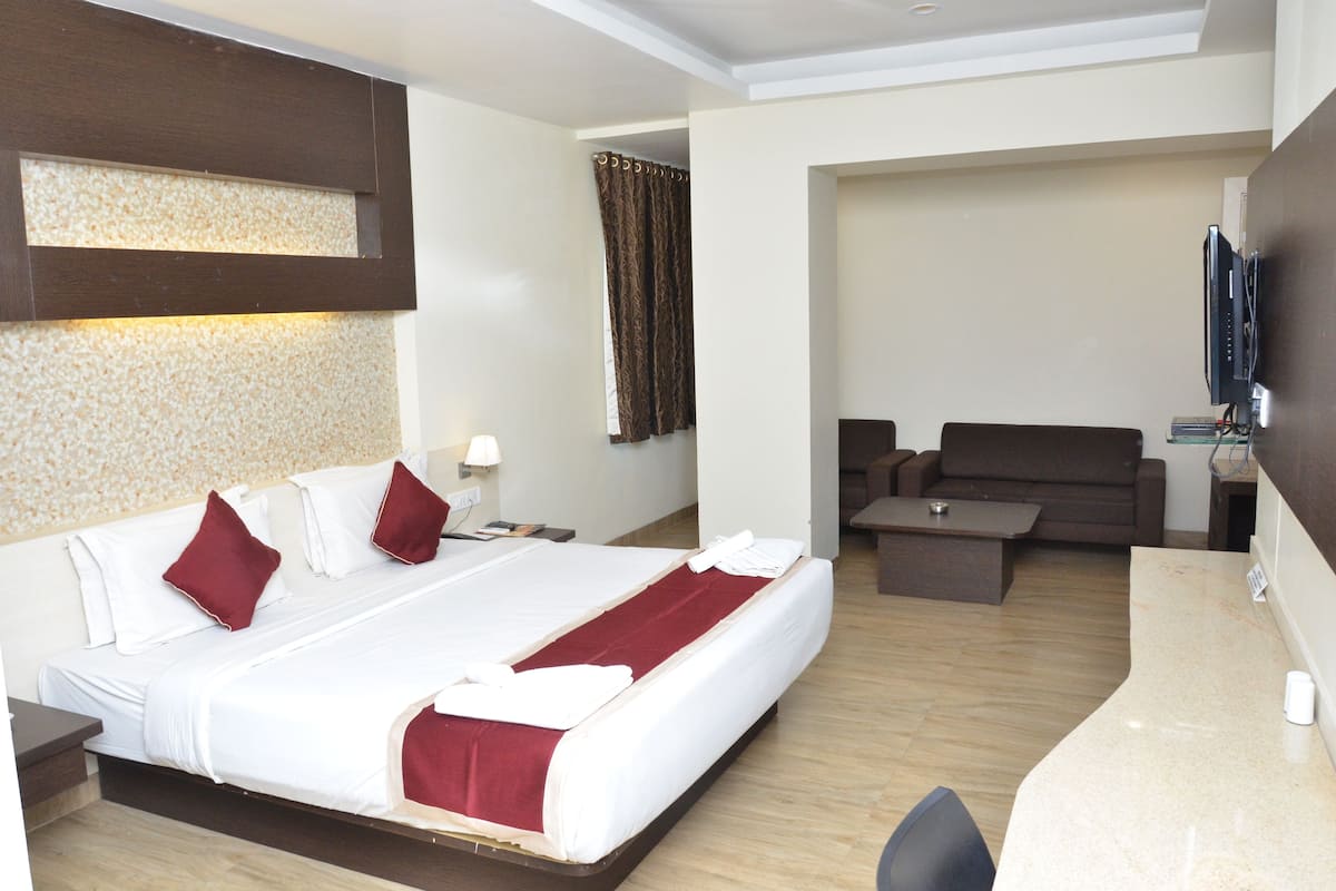 Una habitación de hotel con una cama grande, un sofá, un televisor y un escritorio.