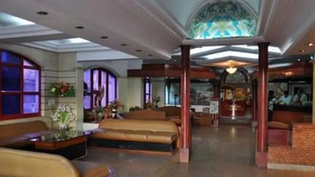 A spacious lobby with a high ceiling, a central seating area, and a reception desk. - Hotel Adarsha Palace (Belagavi)