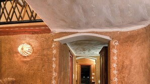 A corridor with a textured wall, a wooden staircase, and a series of spherical light fixtures along the floor. - The Earth At Ranthambore (Sawai Madhopur)