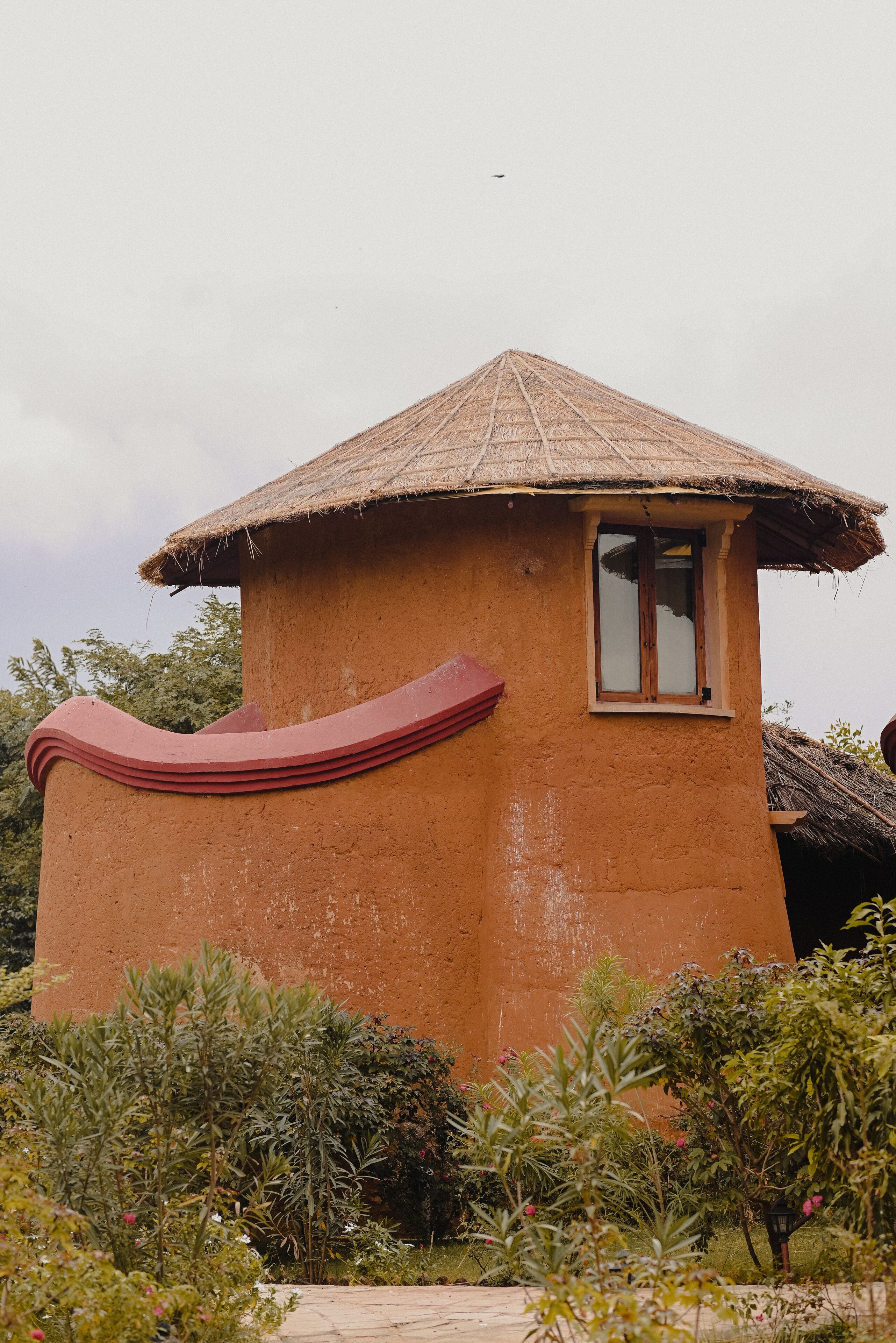 A small, single-story building with a thatched roof and a window.