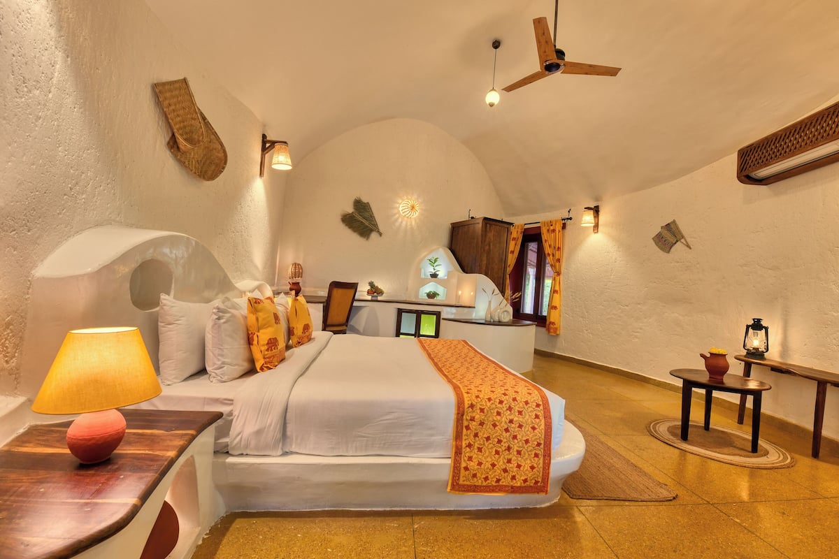 A bedroom with a bed, bedside table, lamp, and a small table with a lantern.