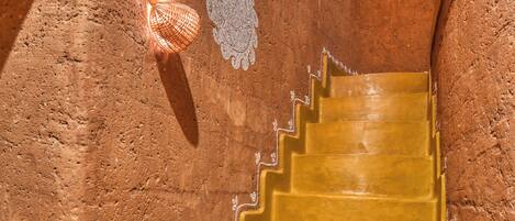 A staircase with a textured wall and decorative lighting fixtures.