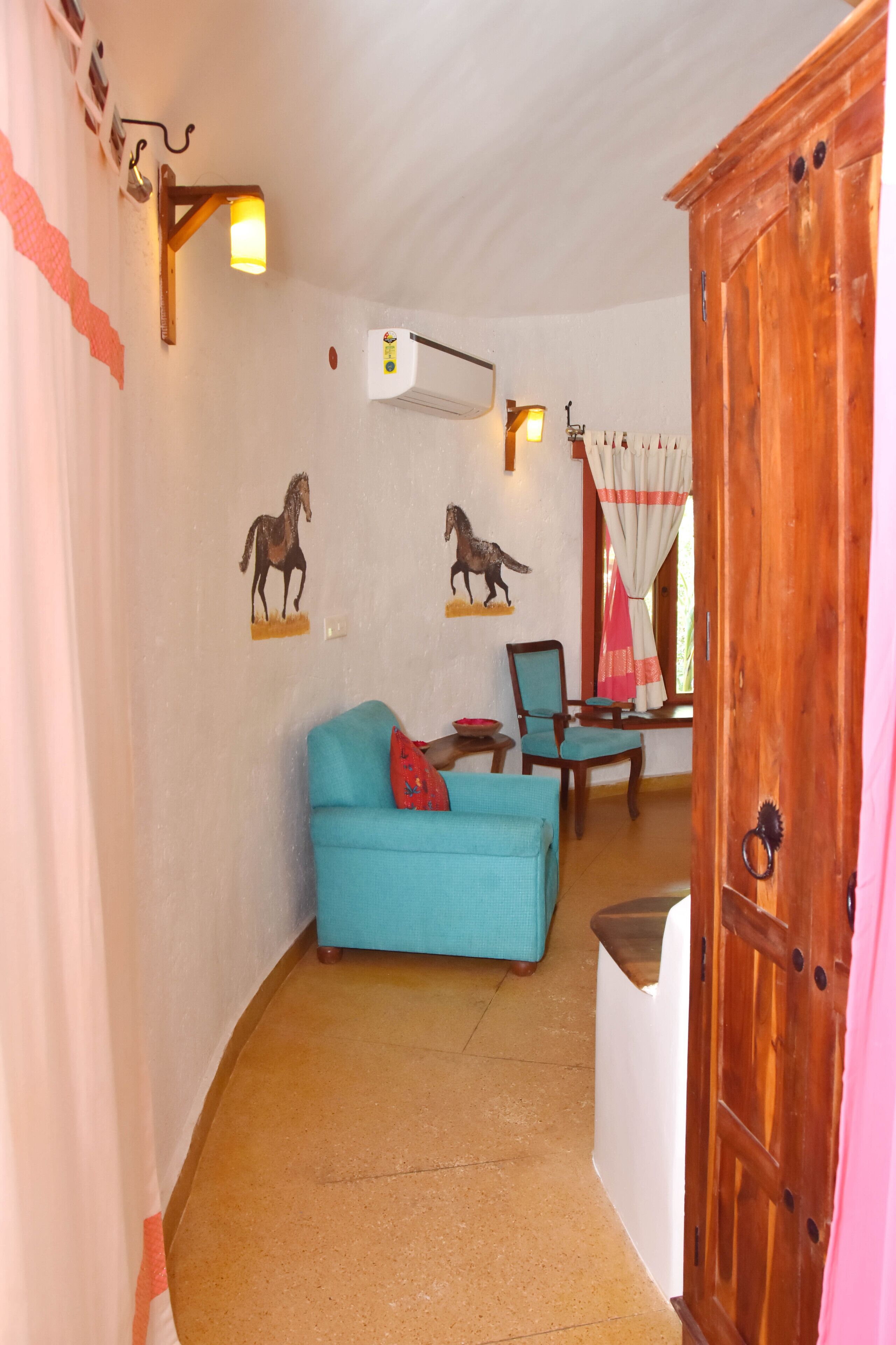 A room with a blue sofa, a wooden cabinet, and wall-mounted horse decals.