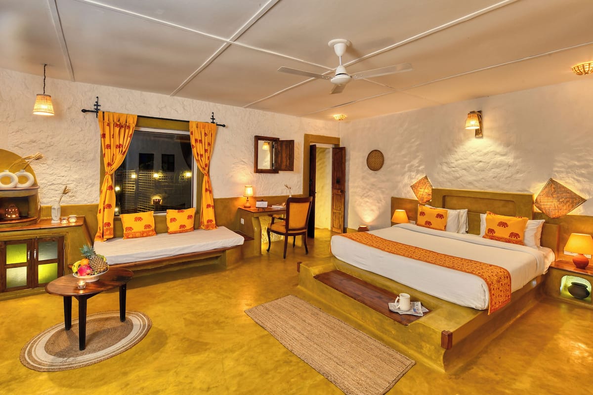 A cozy hotel room with a bed, a desk, a chair, and a small table.