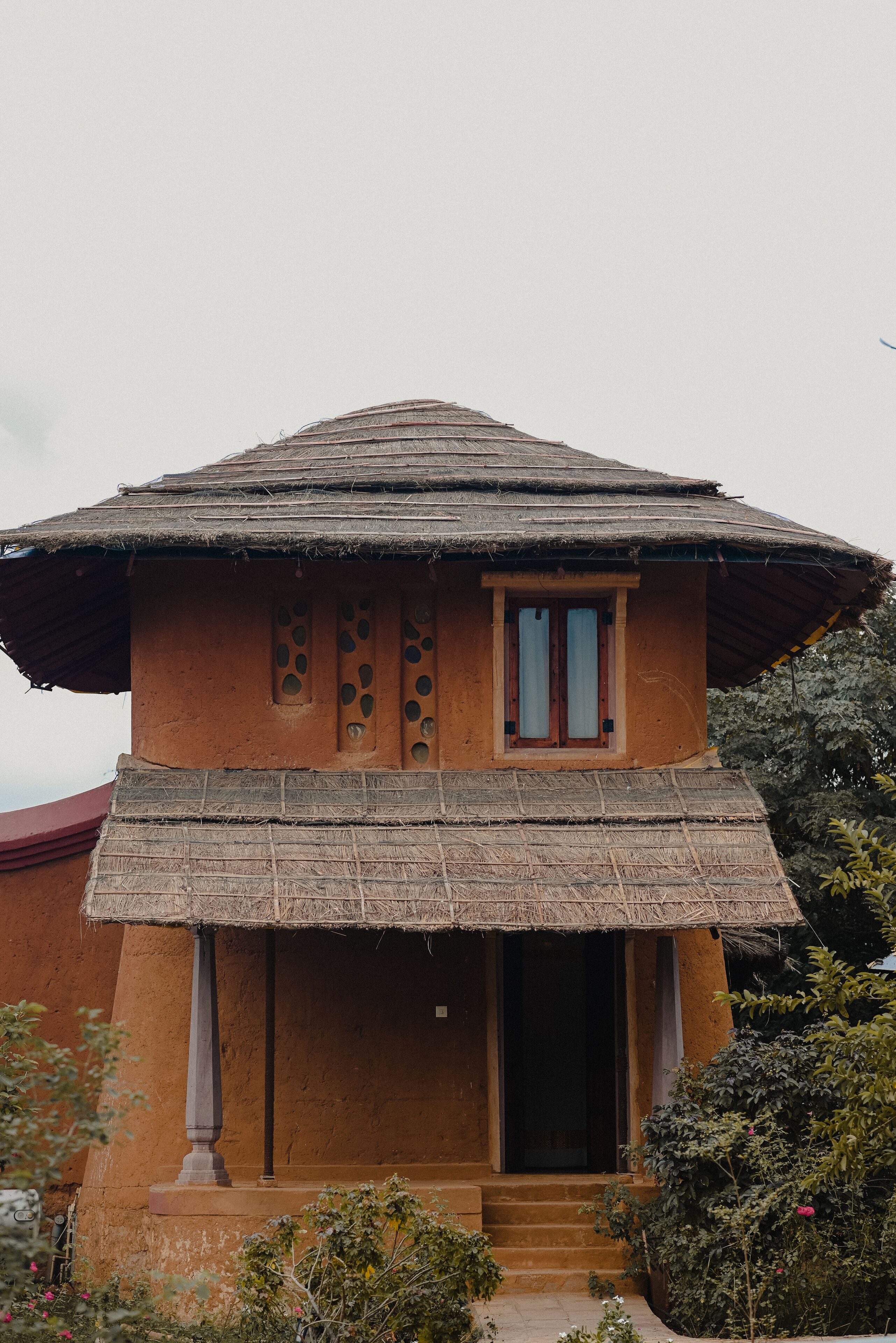 Une maison traditionnelle avec un toit de chaume, une porte en bois et un petit porche.