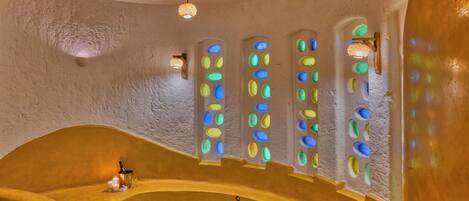 A spa with a large oval hot tub, a small rectangular hot tub, and a wall with colorful circular windows.
