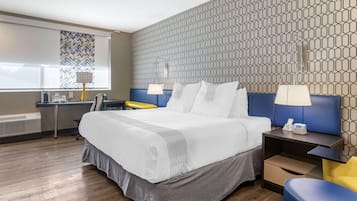 Una habitación de hotel con una cama grande, un escritorio, una silla y una mesita de noche.
