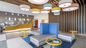A modern lobby with a reception desk, seating area, and unique lighting fixtures.