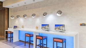 A reception desk with a modern design, featuring a white counter, multiple bar stools, and pendant lighting.