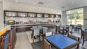 A modern restaurant with a long counter, multiple seating areas, and a view of the outdoors.