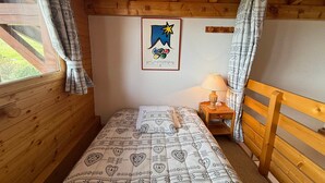 A cozy wooden room with a bed, a nightstand, and a poster on the wall. - South Apartment, 8 pers, 44m², panoramic slopes (Les Saisies)