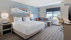 Une chambre d’hôtel avec un grand lit, un bureau, une chaise et un téléviseur.