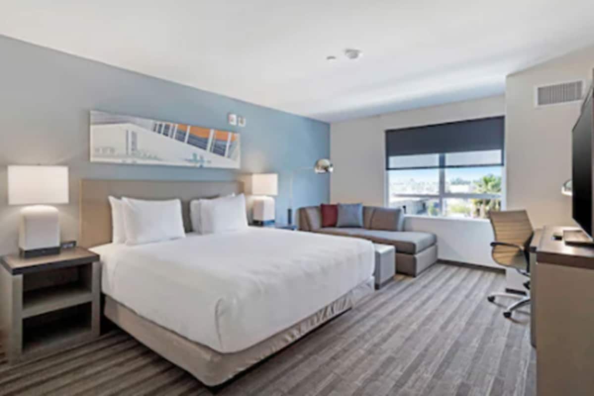 Une chambre d’hôtel avec un grand lit, un bureau, une chaise et un téléviseur.