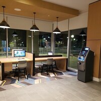 Un moderno ufficio con due scrivanie, sedie, lampadari a sospensione e un chiosco self-service.