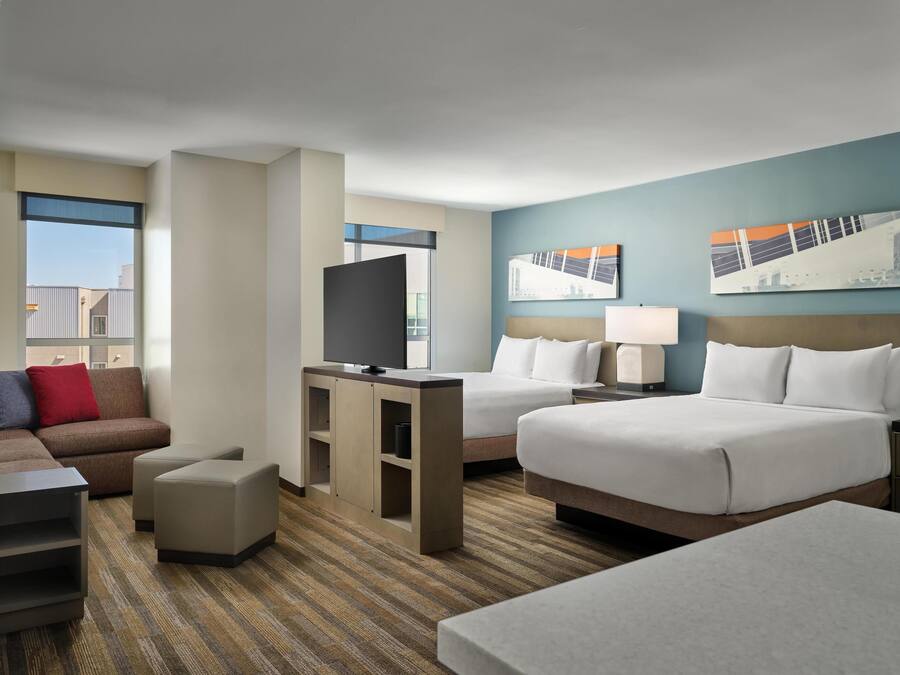 Una habitación de hotel con dos camas, un televisor sobre un soporte, un escritorio y un sofá.