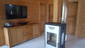 A wooden cabin interior with a television, a radio, and a wood stove. - Ferienhaus am See in Fleeth (Mirow)