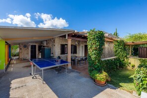 Un cortile con tavolo da ping pong, pareti in pietra e una zona relax coperta.