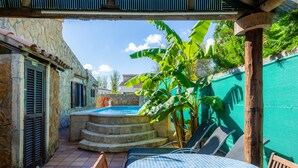 A patio area with a pool, outdoor seating, and a stone wall. - Holiday Home ’Casa Paqui Alcudia’ with Wi-Fi, Garden, Terraces & Pool (Puerto de Alcudia)
