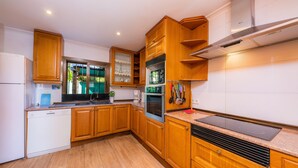 A modern kitchen with wooden cabinets, a built-in oven, and a stainless steel range hood. - Holiday Home ’Casa Paqui Alcudia’ with Wi-Fi, Garden, Terraces & Pool (Puerto de Alcudia)