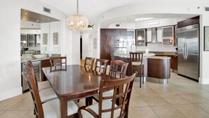 Una cocina amplia con una isla grande, electrodomésticos de acero inoxidable y un comedor con mesa y sillas de madera.